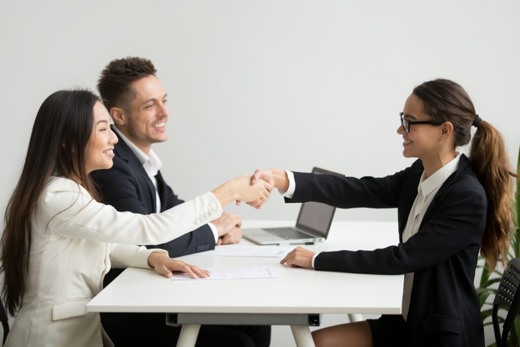 Free photo smiling diverse businesswomen shake hands at group meeting, deal concept